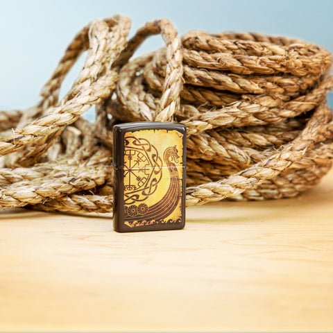 Lifestyle image of Viking Warship Design Brown Windproof Lighter with rope in the background