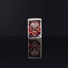 Lifestyle image of Skull Design Mercury Glass Windproof Lighter standing in a black background, with its design reflecting on the group.