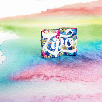 Lifestyle image of Zippo Floral Design 540 Color Windproof Lighter, showing the front and back of the design with the lighters standing on a multicolor surface