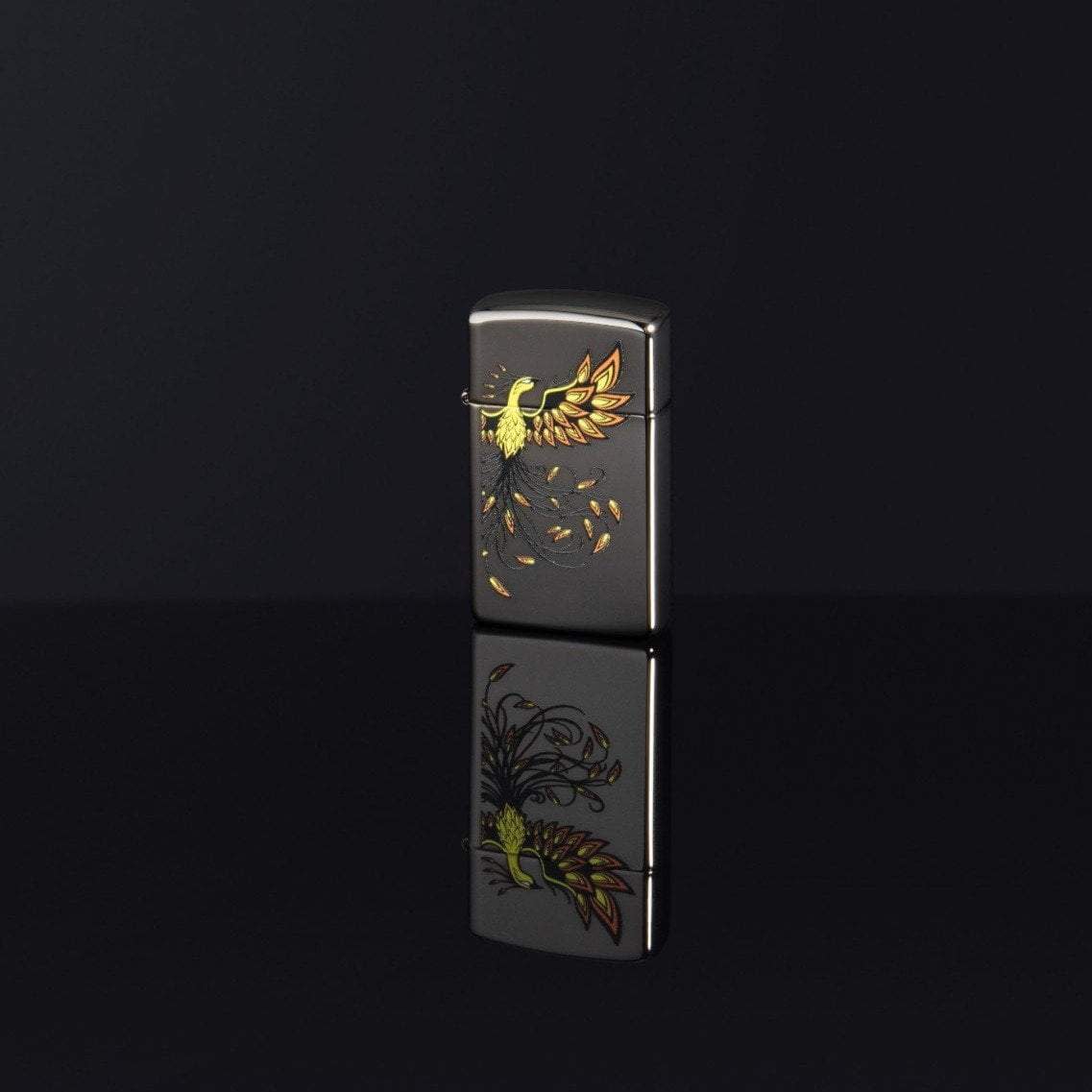 Lifestyle image of Slim® Phoenix Design Black Ice® Windproof Lighter standing on a black surface, with the design reflecting off the bottom.