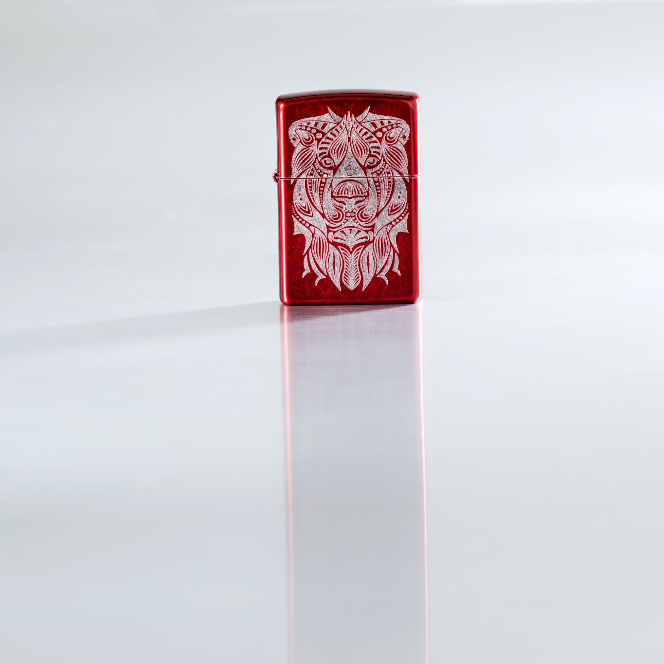 Lifestyle image of Lion Tattoo Design Candy Apple Red Windproof Lighter standing on a reflective surface