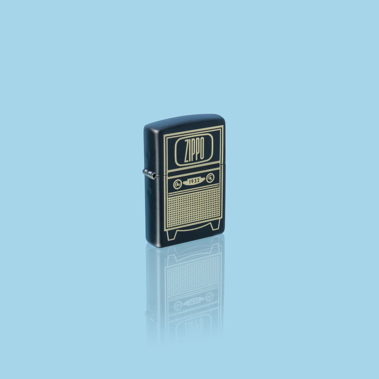 Glamour shot of Zippo Vintage TV Design Black Matte Windproof Lighter standing in a blue scene.