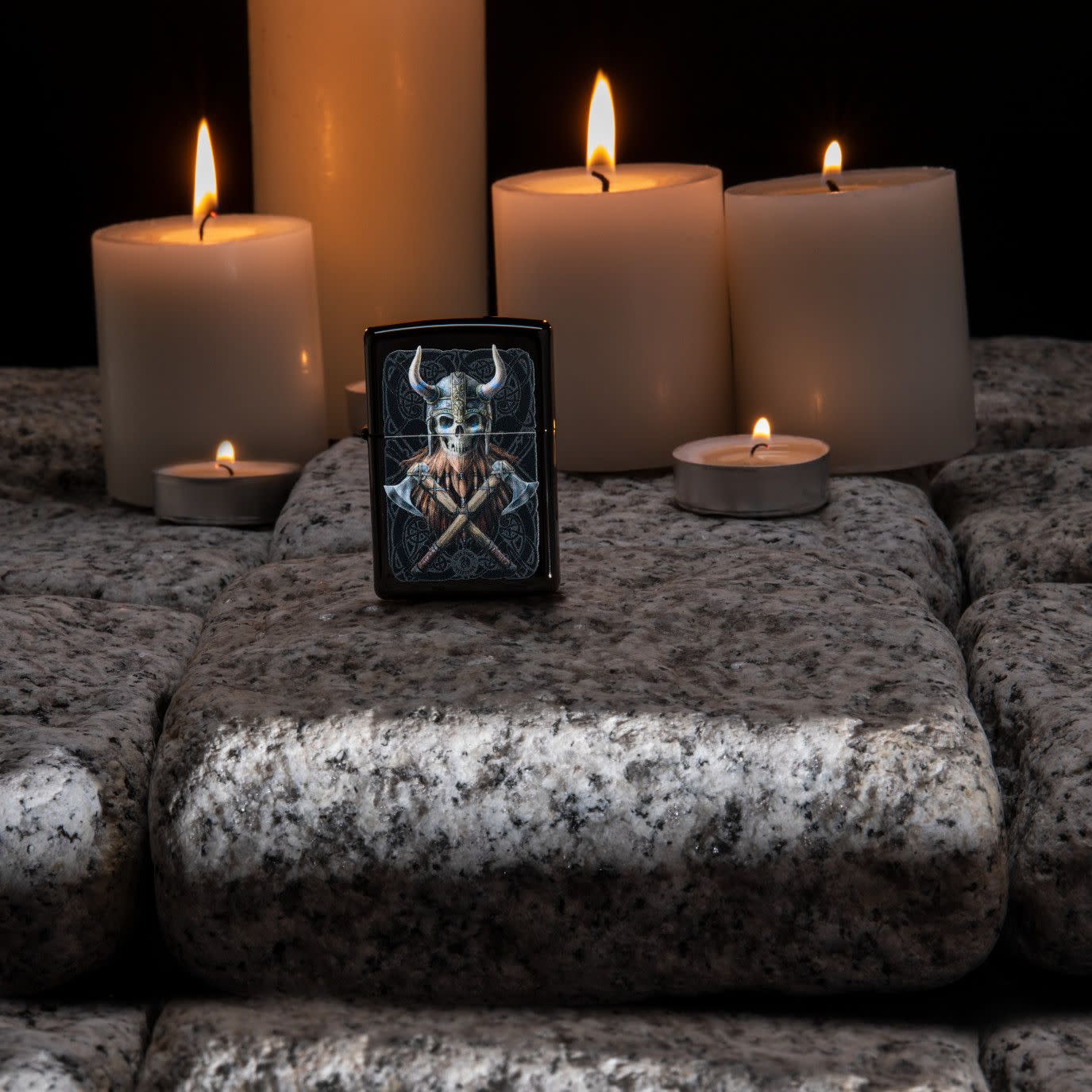 Lifestyle image of Anne Stokes Viking Skull Lighter standing on cobblestone with lit candles in the background